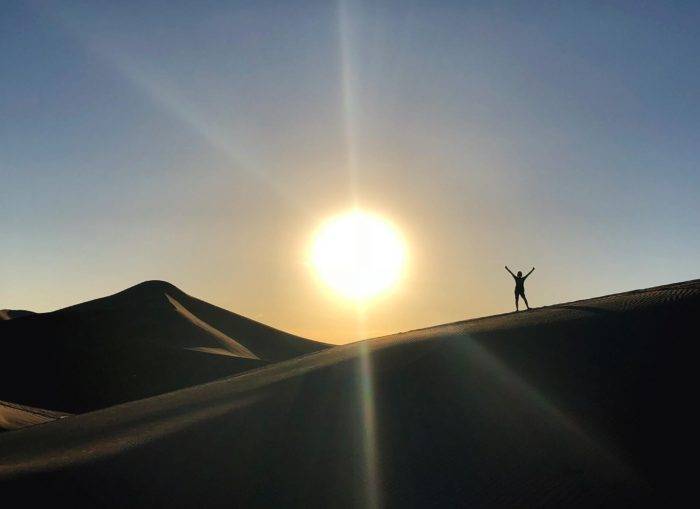 person standing on sand dune