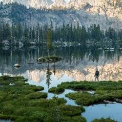 A man standing near a mountain lake