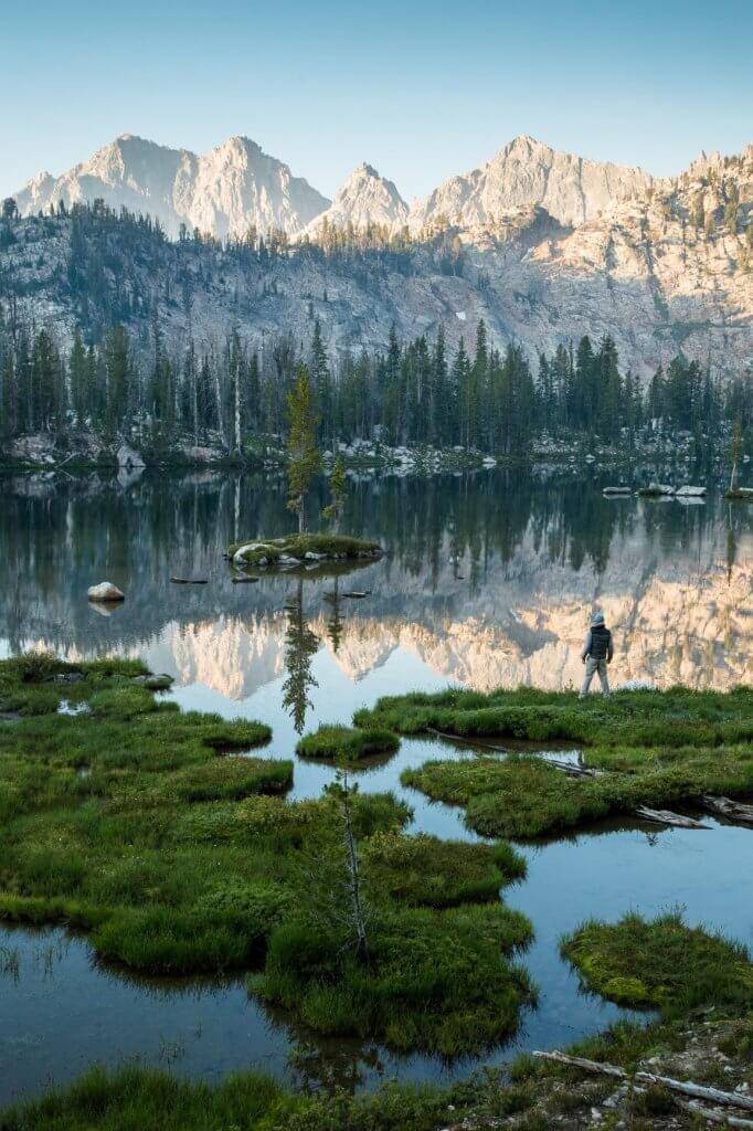 A man standing near a mountain lake