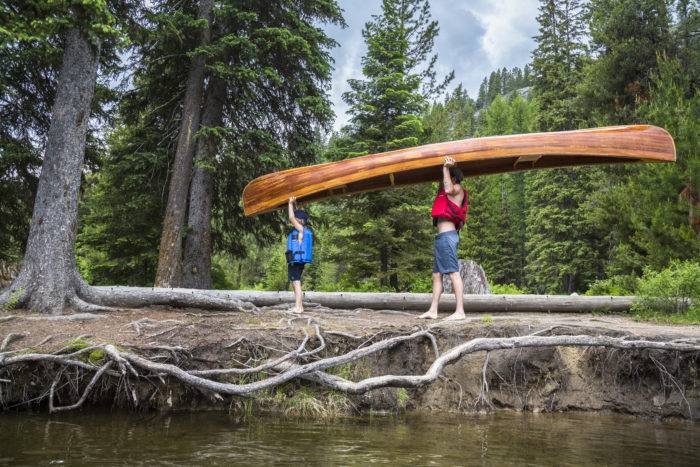 A father and son carrying their canoe down to the lake.