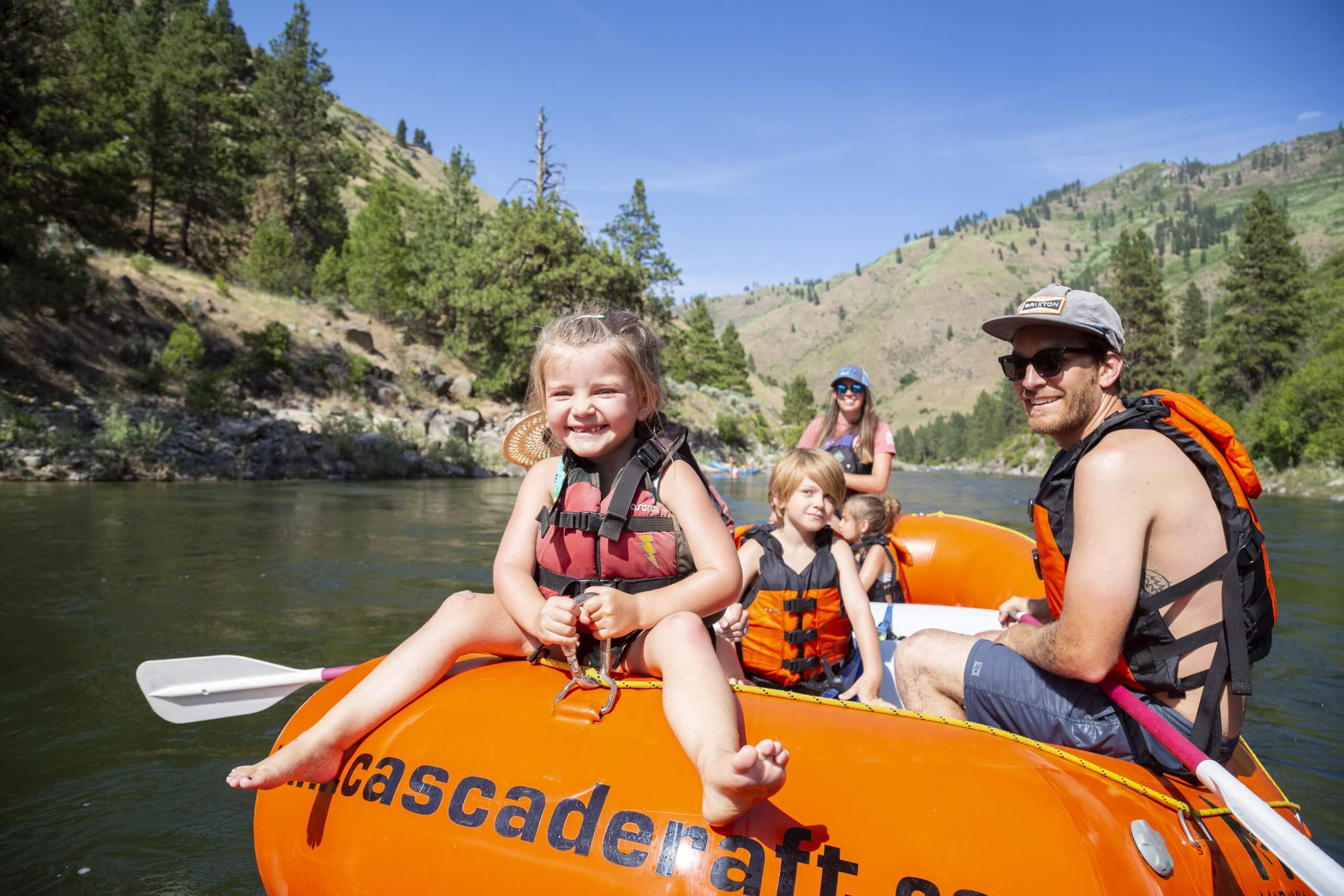 A girl riding on the front of the raft on a river.