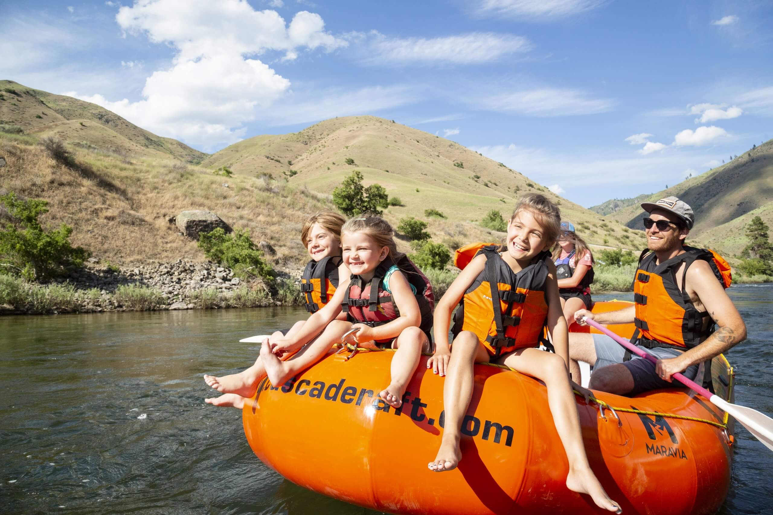 A girl riding on the front of the raft on a river.