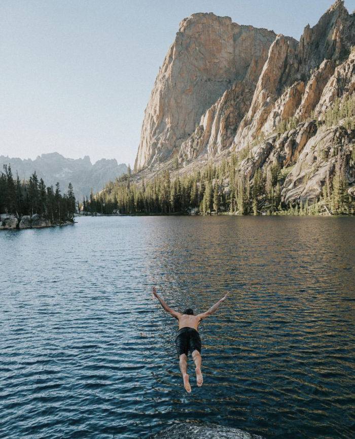 A man diving into a mountain lake.