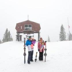 family at top of ski hill with skis