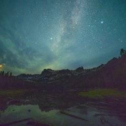 A dark turquoise night sky filled with stars stretches out over the Sawtooth Mountains.