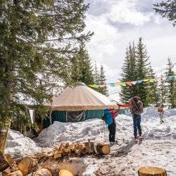 Two hikers in snow gear high-five outside of the Pioneer Yurt during winter.