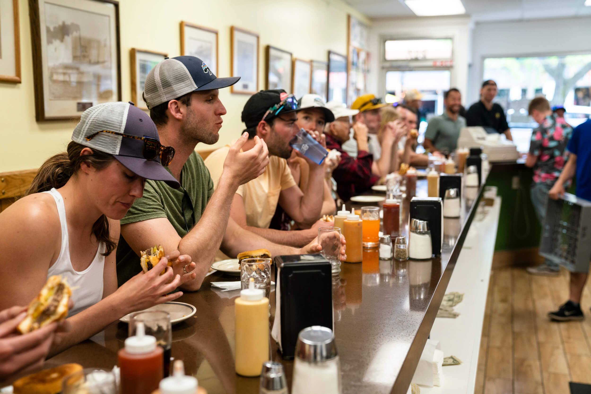 people sitting and eating hamburgers at the restaurant counter at Hudson's