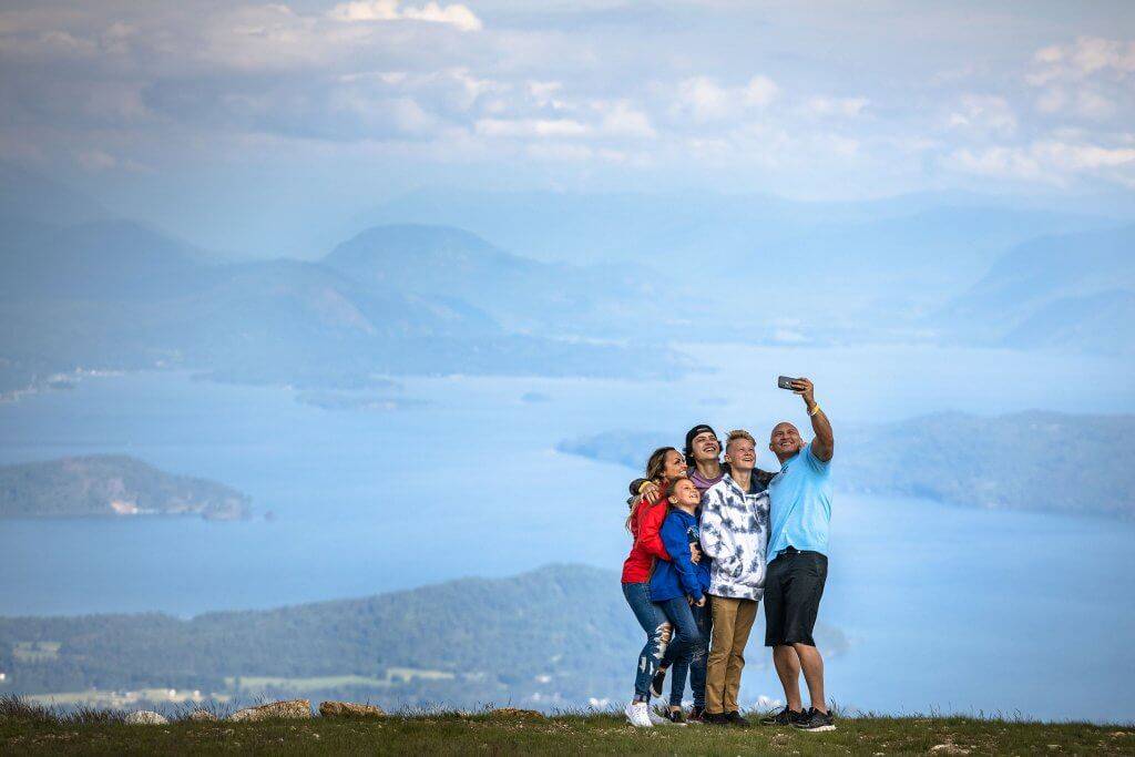 Family of five taking a selfie with Sandpoint and lake pend orielle in the background
