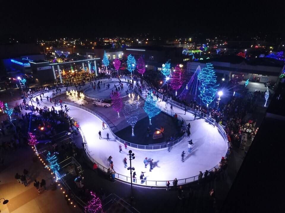 An aerial view of people skating at Indian Creek Plaza Ice Skating Ribbon surrounded by trees with colorful lights.