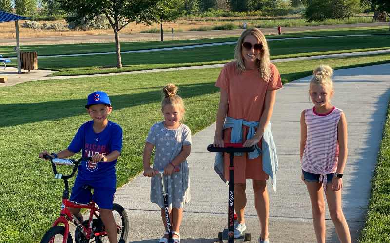 woman and three children riding bikes and scooters at Mallard Park