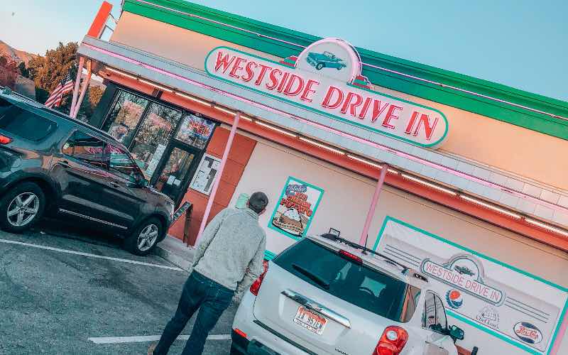 front view of Westside Drive-In with two cars and a man in the parking lot