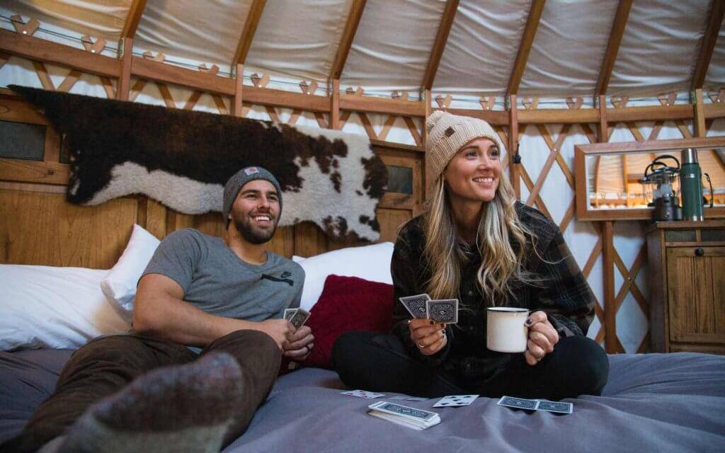 Relaxing on a bed, playing cards in Willow Glamping Yurt