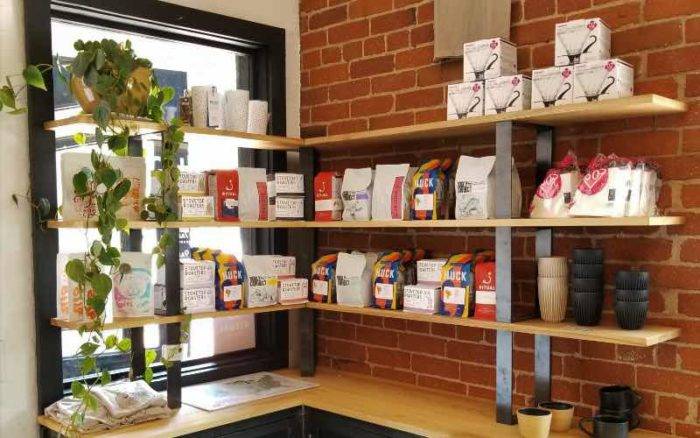 bags of coffee beans and cups arranged on wall mounted shelves