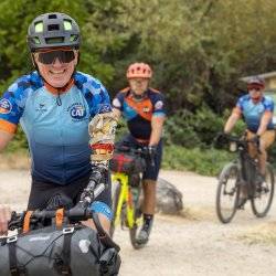 A man, Willie Stewart, with a prosthetic arm, smiles as he rides his bike.