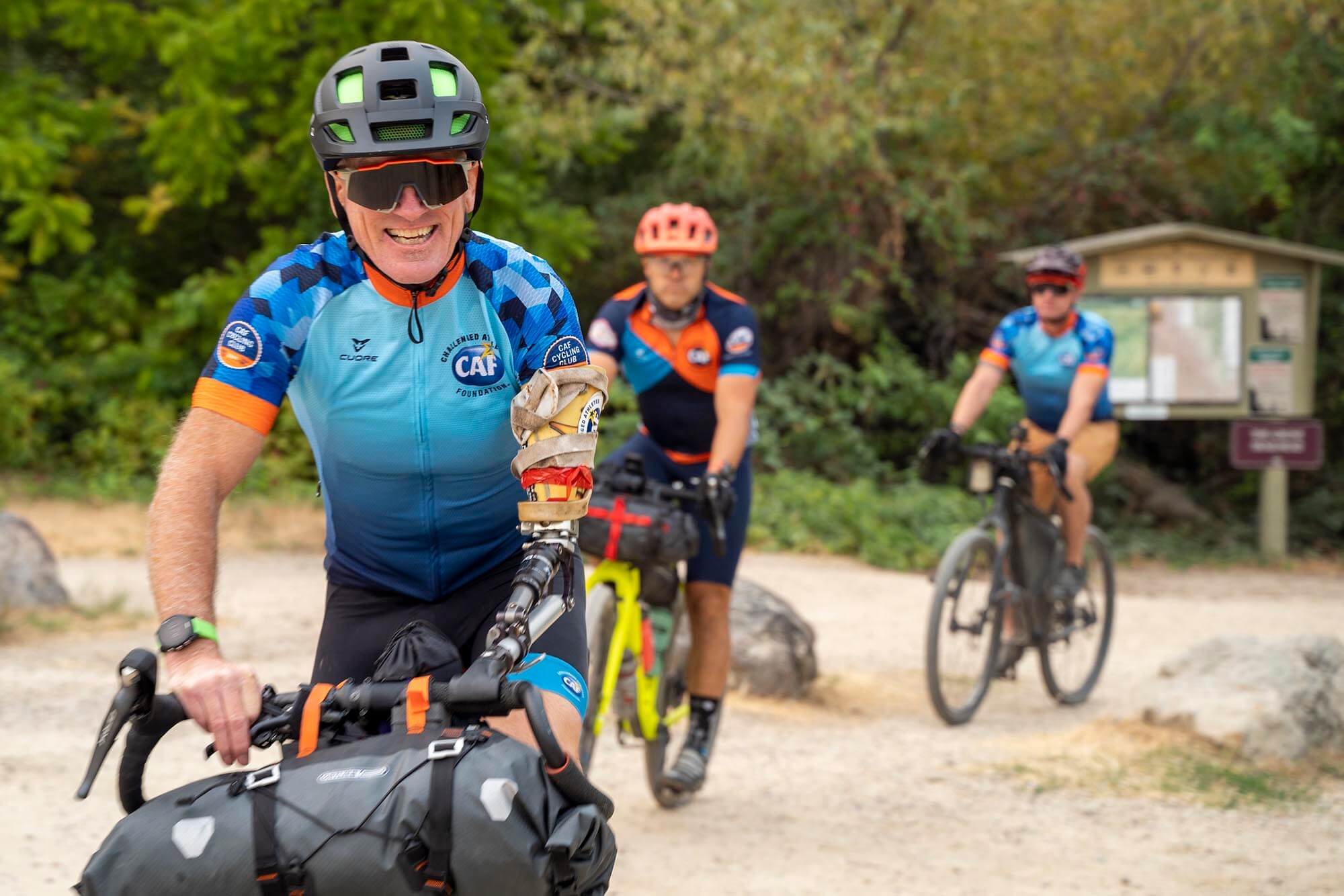 A man, Willie Stewart, with a prosthetic arm, smiles as he rides his bike.