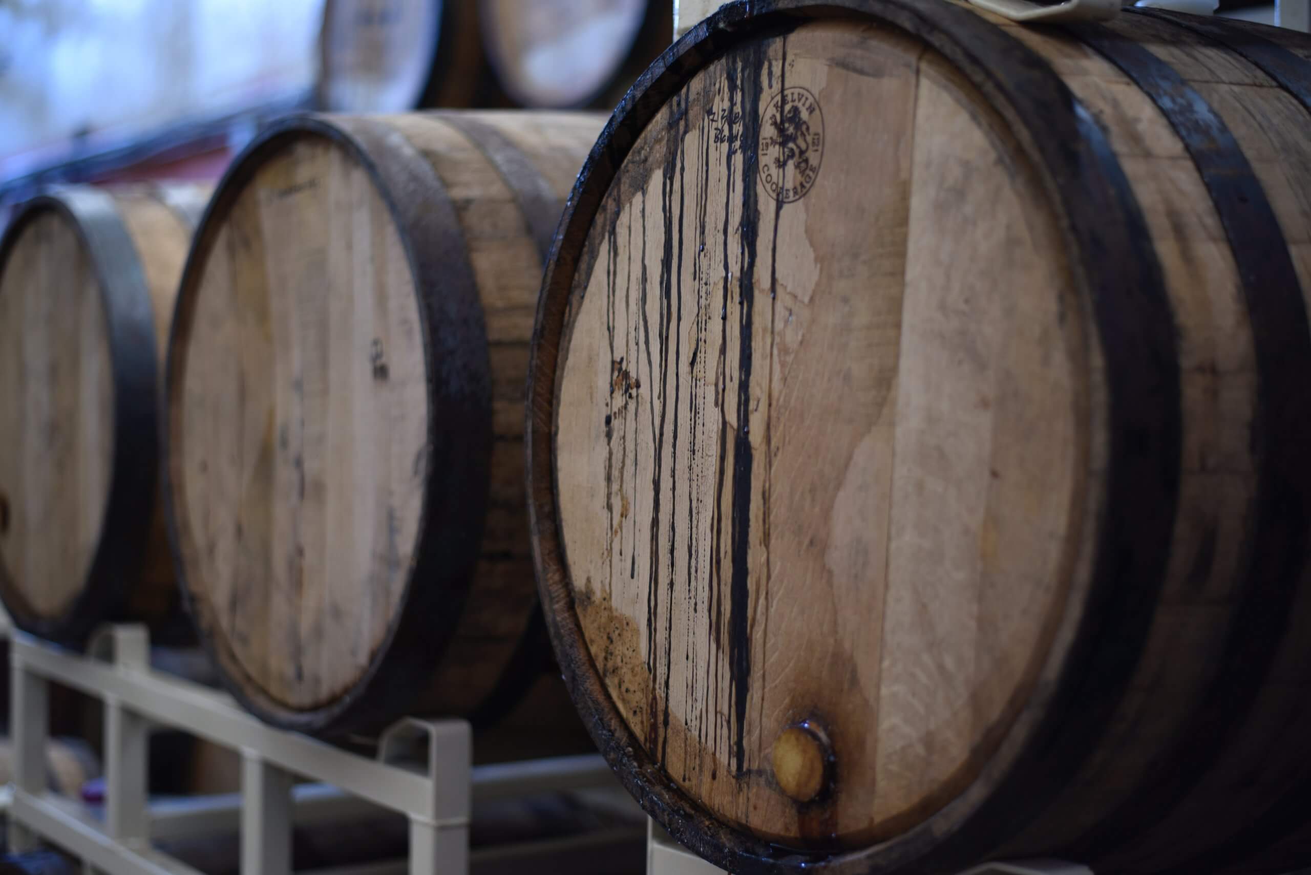 Up-close view of three distillery barrels laying on their sides.