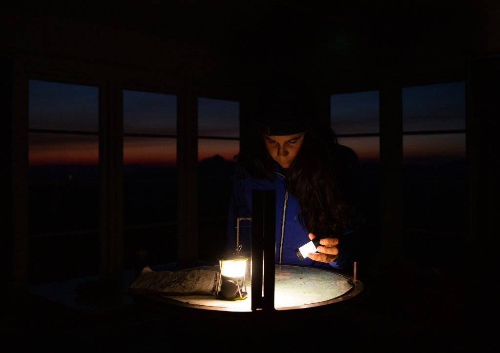 woman sitting inside fire lookout at night