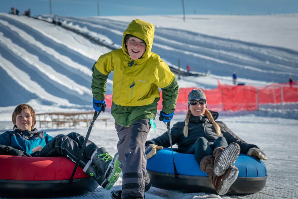 boy pulling people on snowy tubing hill