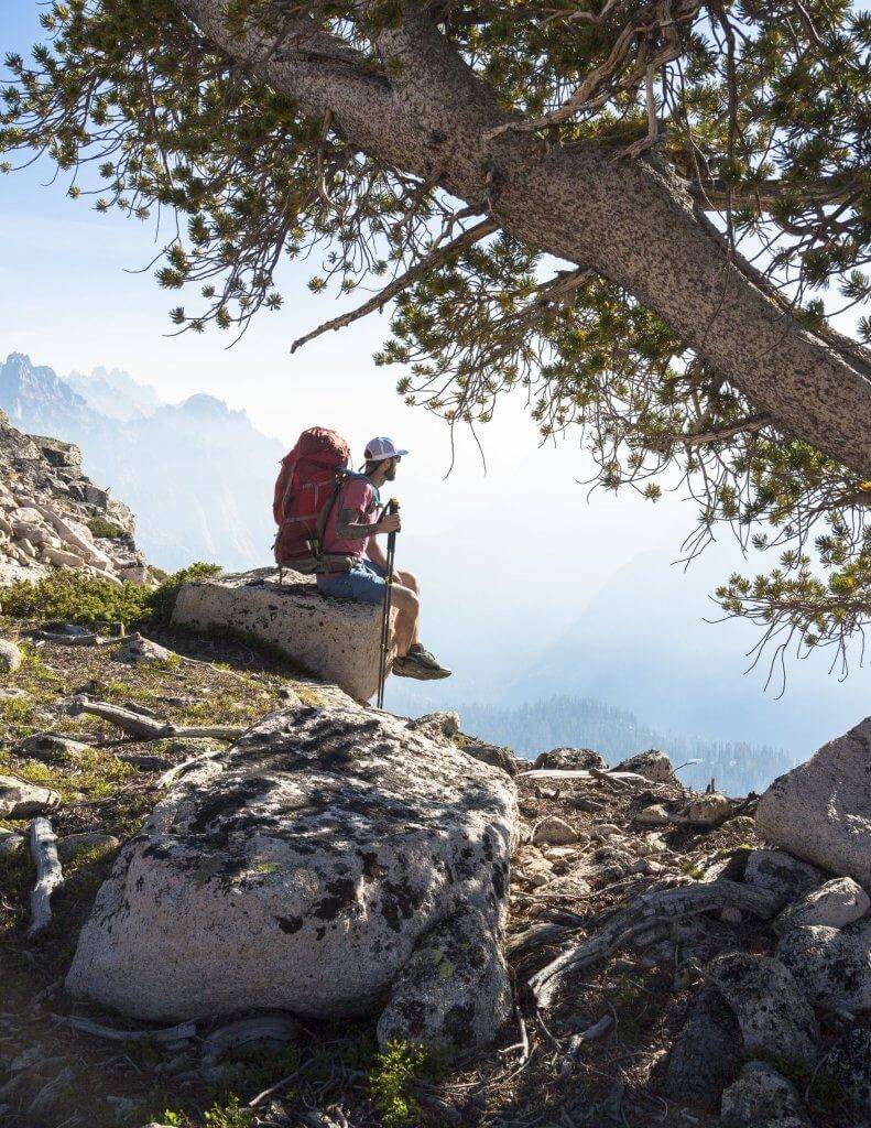 A man sits on a rock overlooking the valley below in the Sawtooth Mountains.