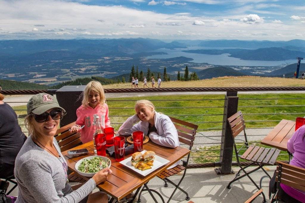 mom and kids sitting at table over looking lake pend oreille at schweitzer