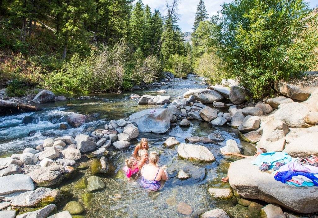 mom and two kids sitting it natural riverside hot spring