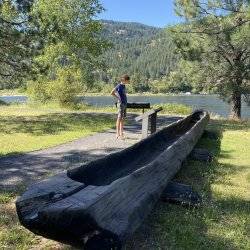 A child standing next to historical canoe reading a informational sign.