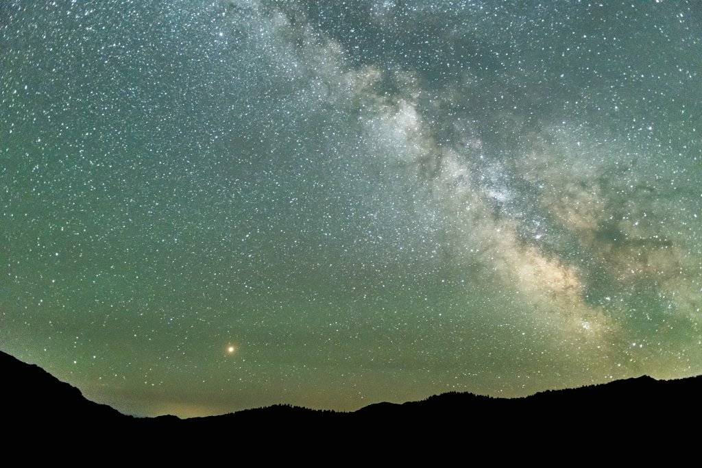 A green starry night sky of the Milky Way and Saturn at the Central Idaho Dark Sky Reserve