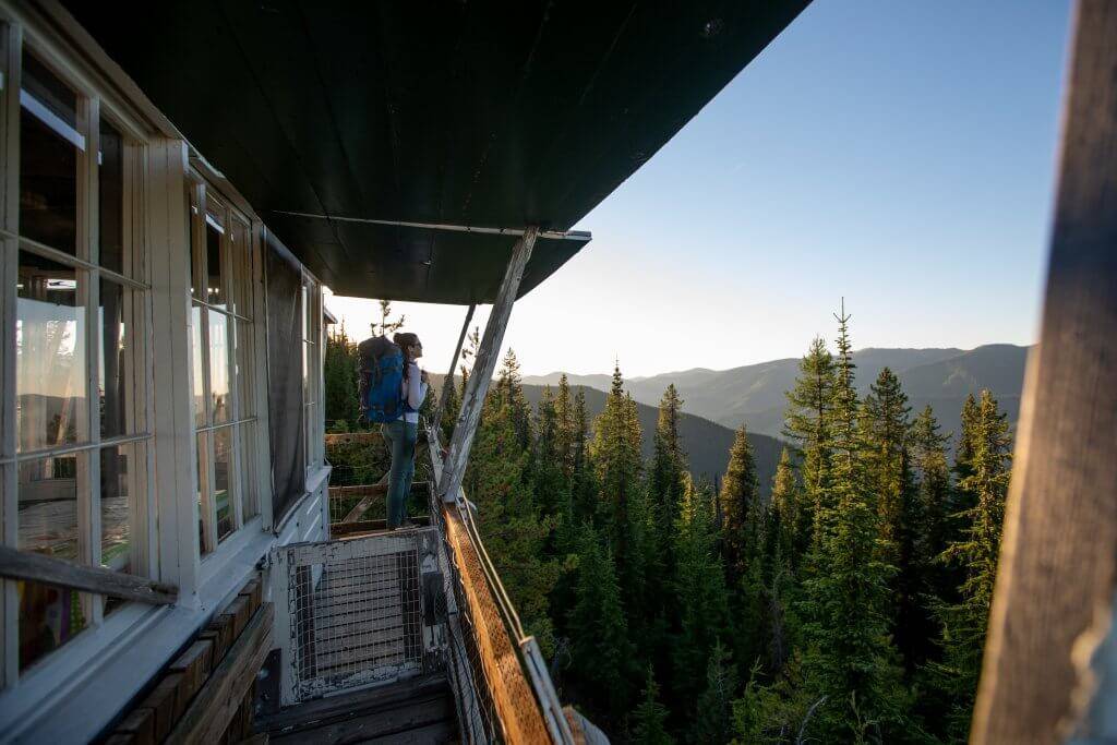 woman with backpack on deck of fire lookout