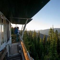 woman with backpack on deck of fire lookout