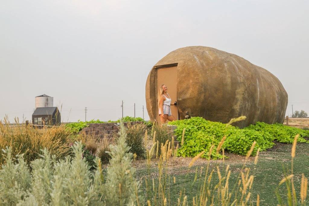 woman standing at door to large idaho potato shaped hotel