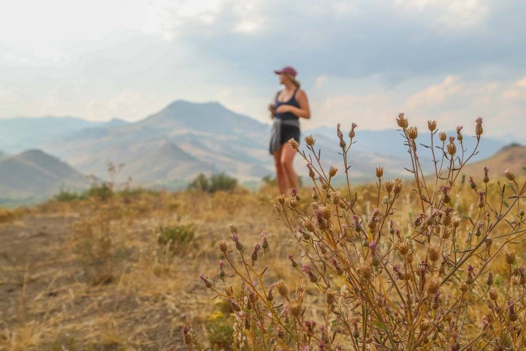 woman standing on hill with mountains in background