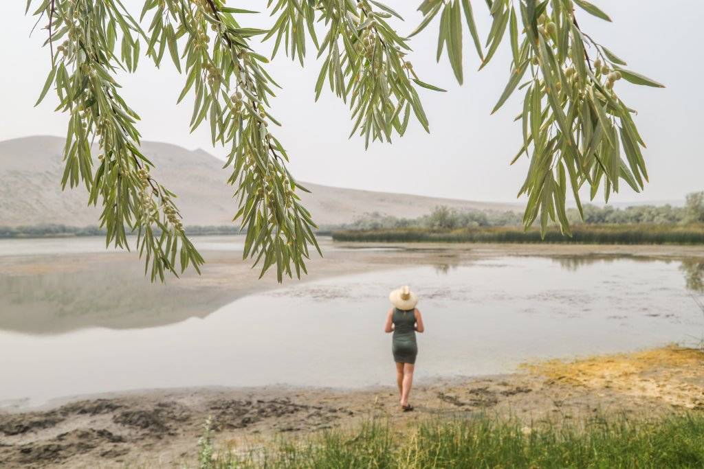 woman standing on edge of small lake