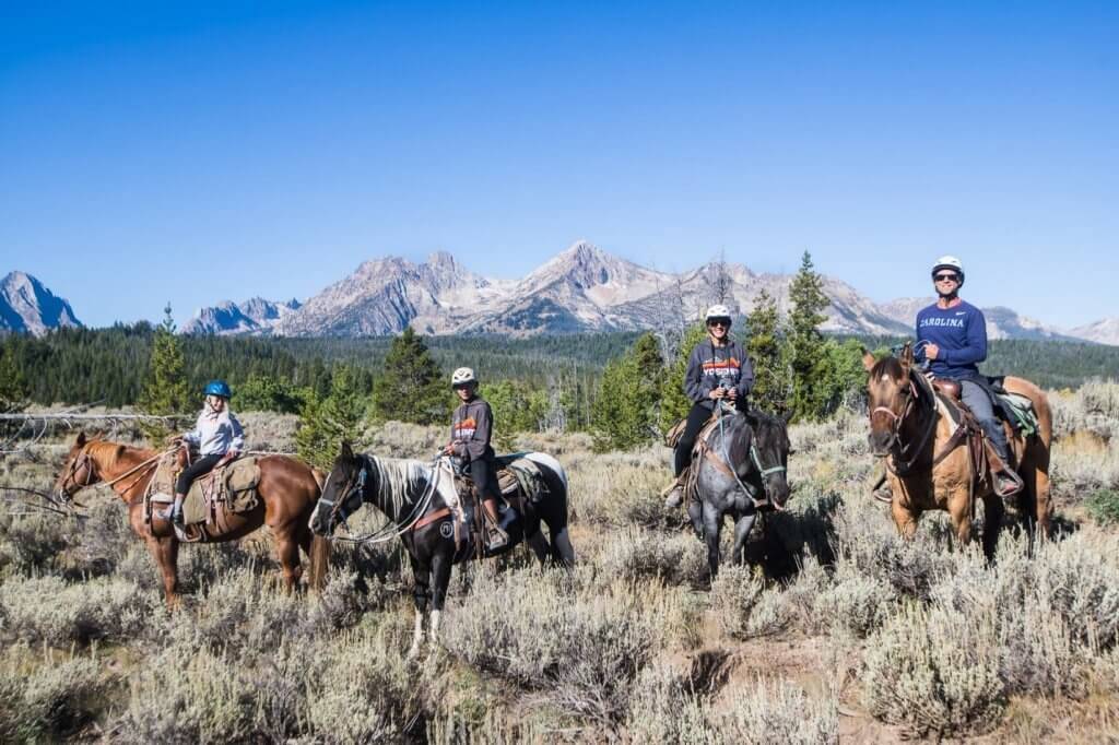 four people on horseback with mountains in background