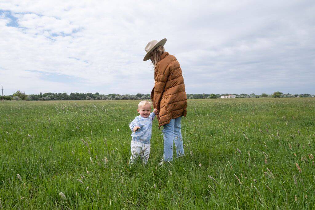 mom walking with small child in tall grass