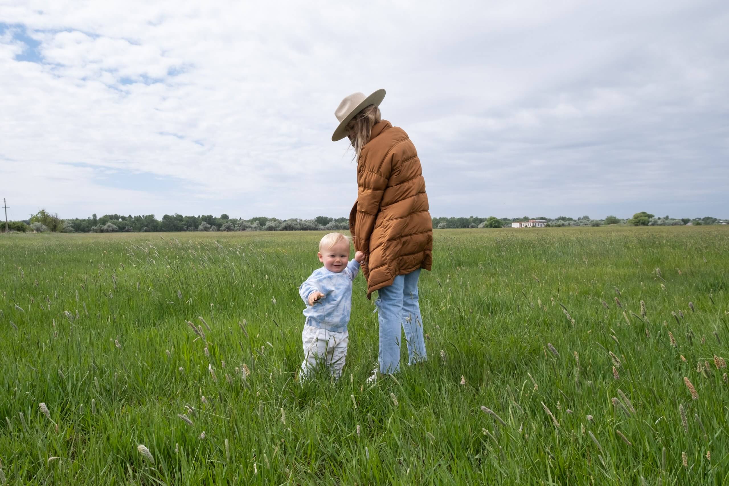 mom walking with small child in tall grass