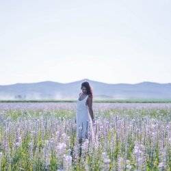 A woman poses for a photo in a field of camas lily blooms.