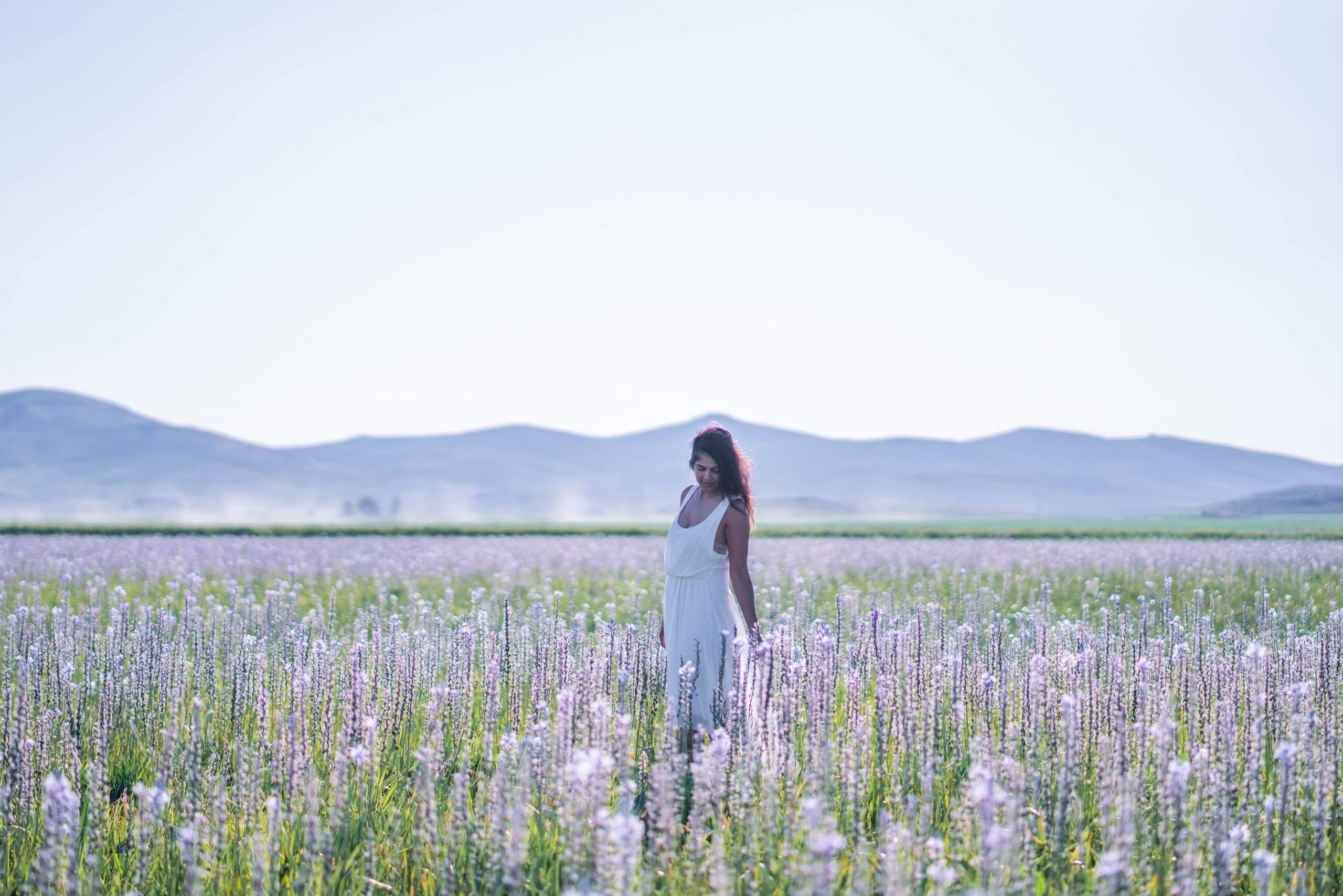 A woman poses for a photo in a field of camas lily blooms.