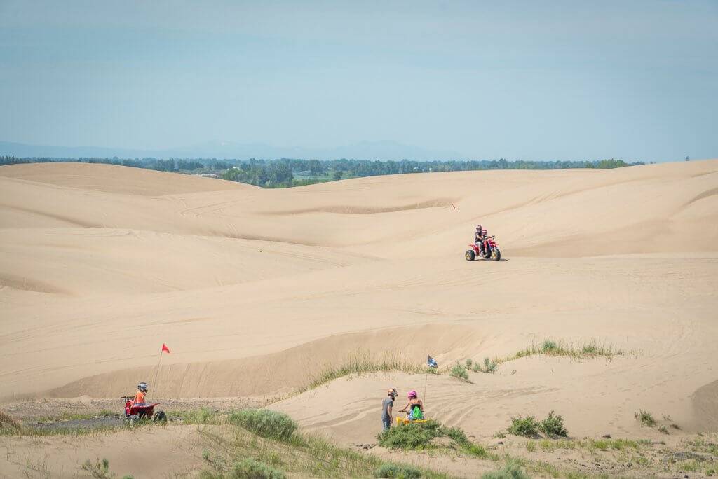 people on atvs riding on sand dunes