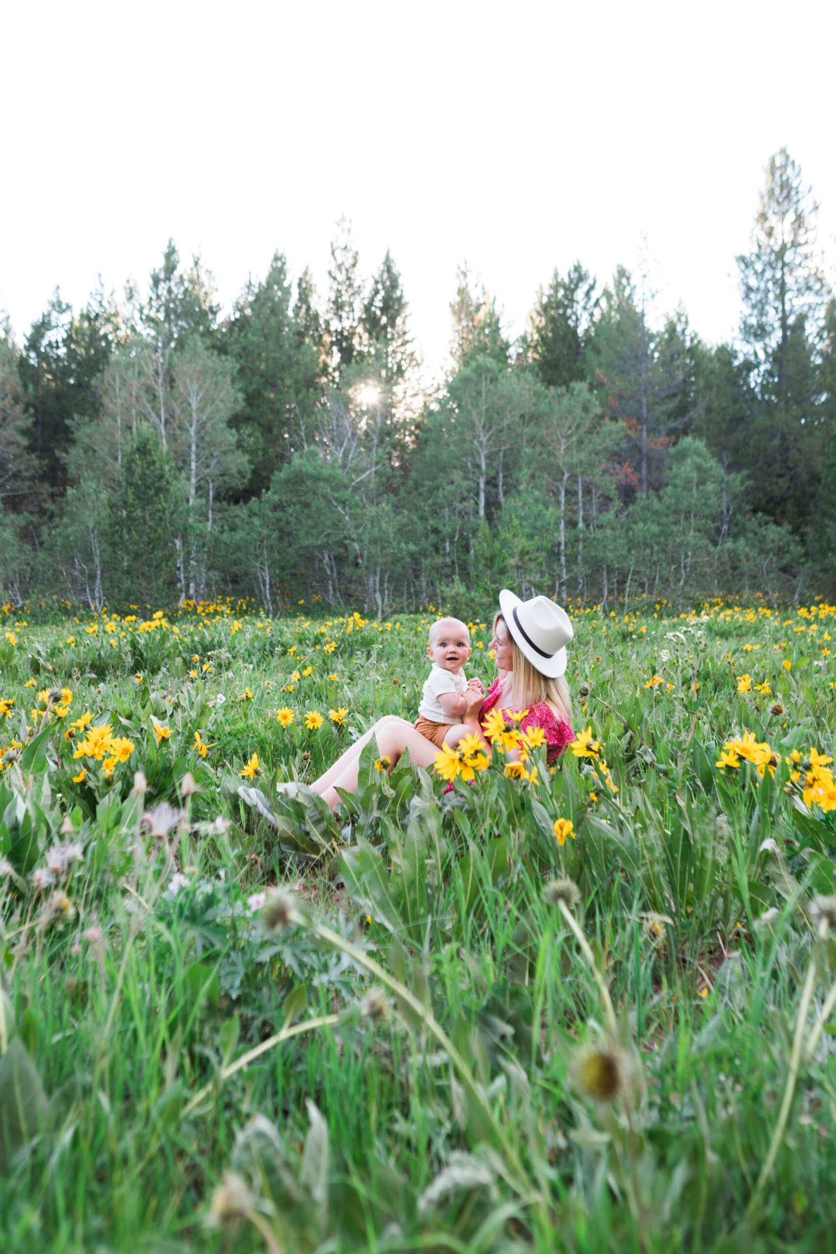 woman and baby sitting in field of wildflowers