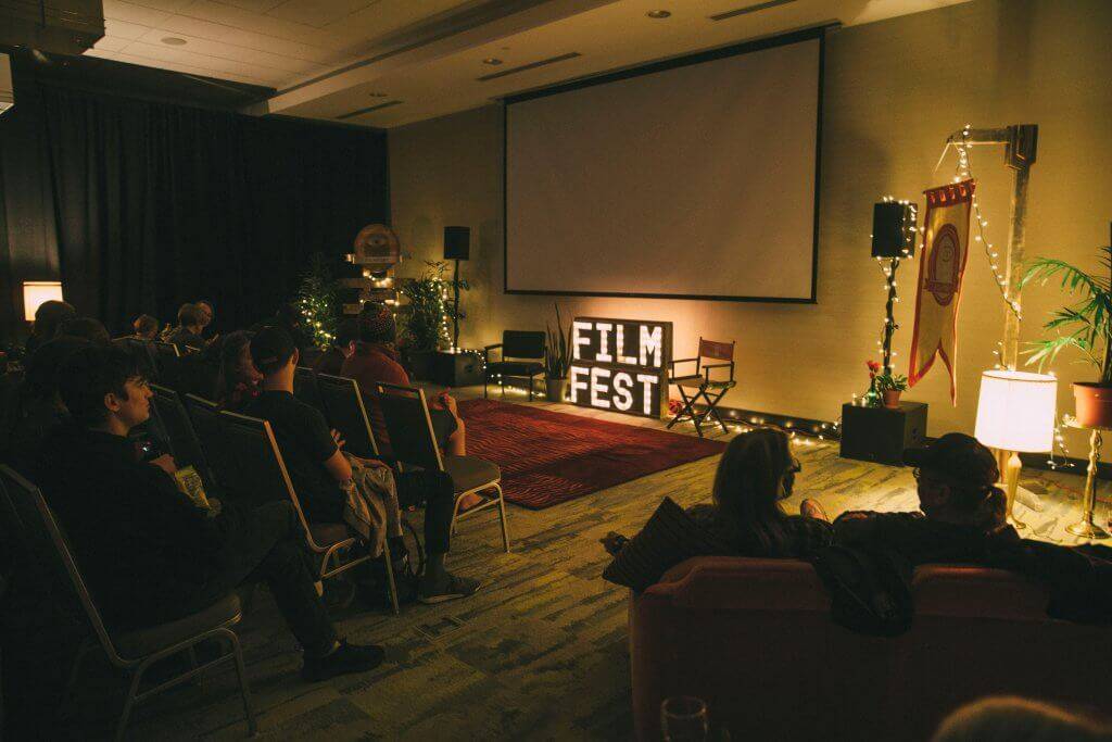 people sitting in room with movie screen