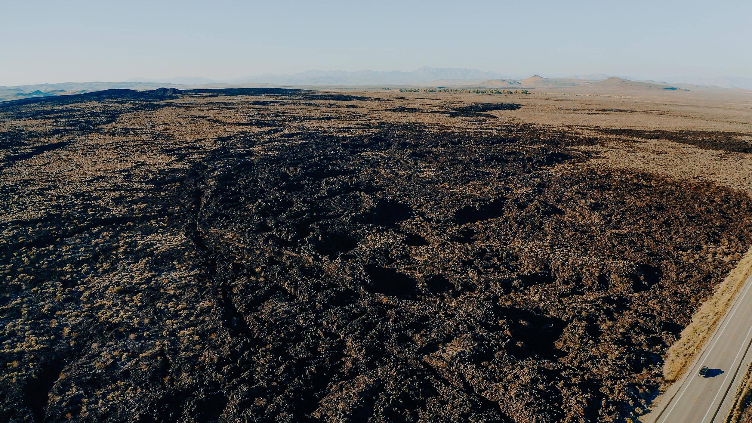 overhead view of lava flows and a crater area beside a highway