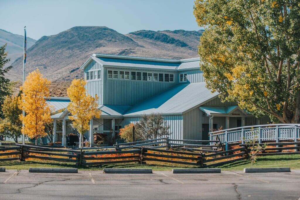 view of a parking lot in front of a wooden building surrounded by a wooden fence with mountains in the background