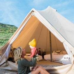 mom sitting outside glamping tent with baby