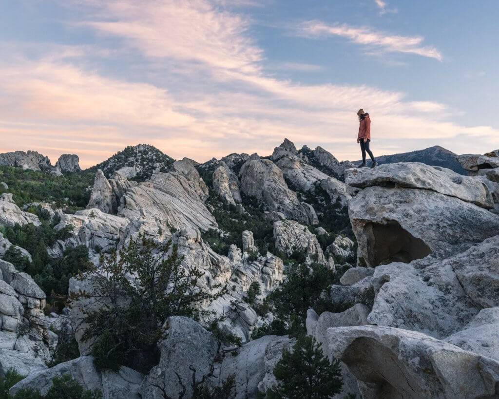 woman standing on large rocks at sunset