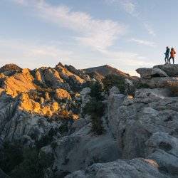 people standing on rocks at sunrise