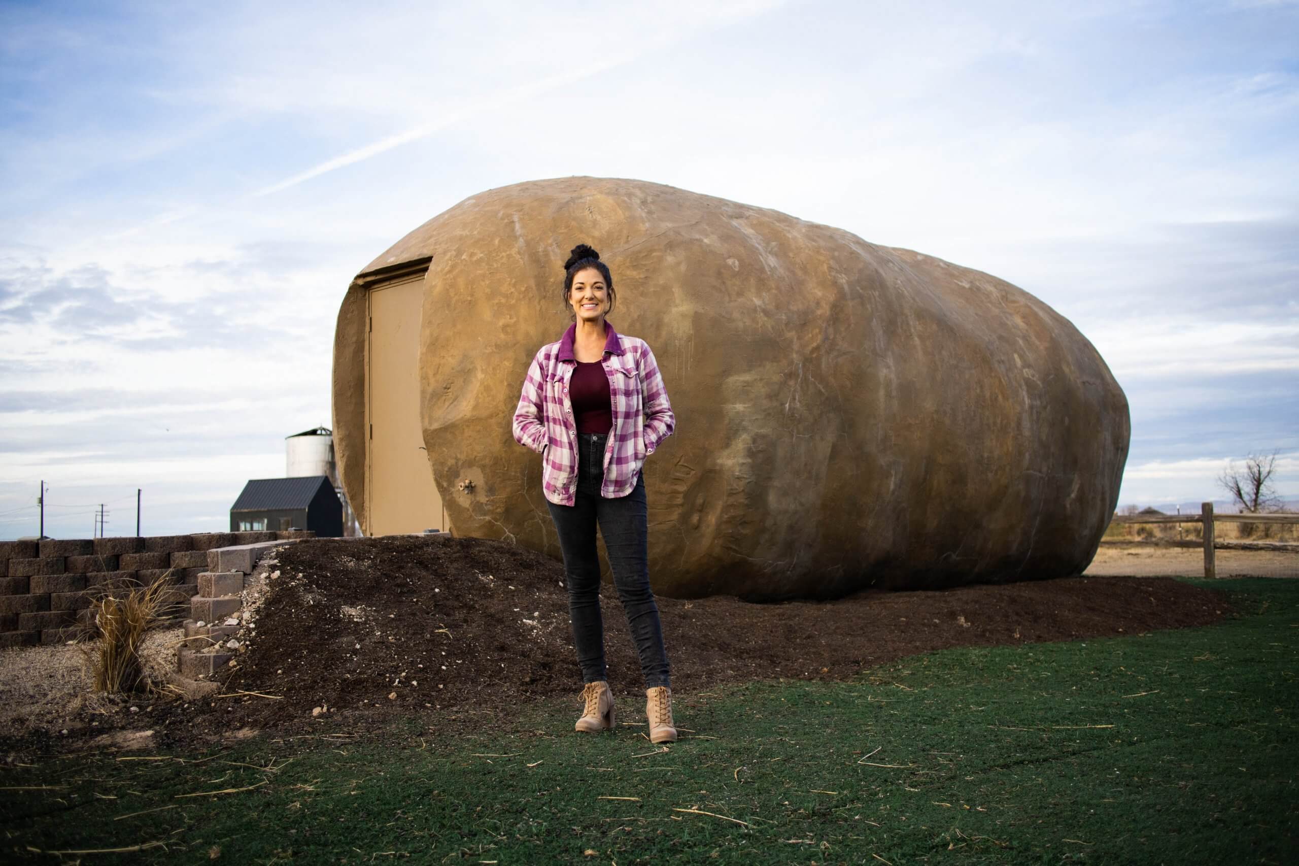 Owner and designer, Kristie Wolfe, wears a flannel purple jacket as she stands in front of her vision turned to life, the Big Idaho Potato Hotel in Boise, Idaho.