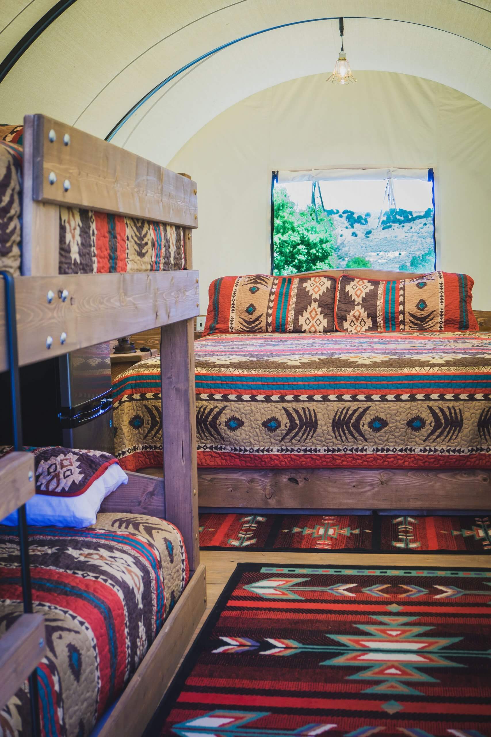 A glimpse of the matching, multi-colored blankets and rug of the interior bedroom of a Conestoga Wagon in Downey.