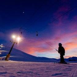 A child on ski pull line during a colorful sunset at Rotarun Ski Area.