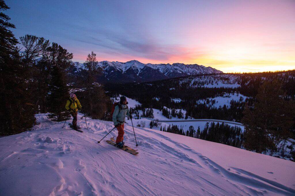 two skiers at the top of a peak at sunrise