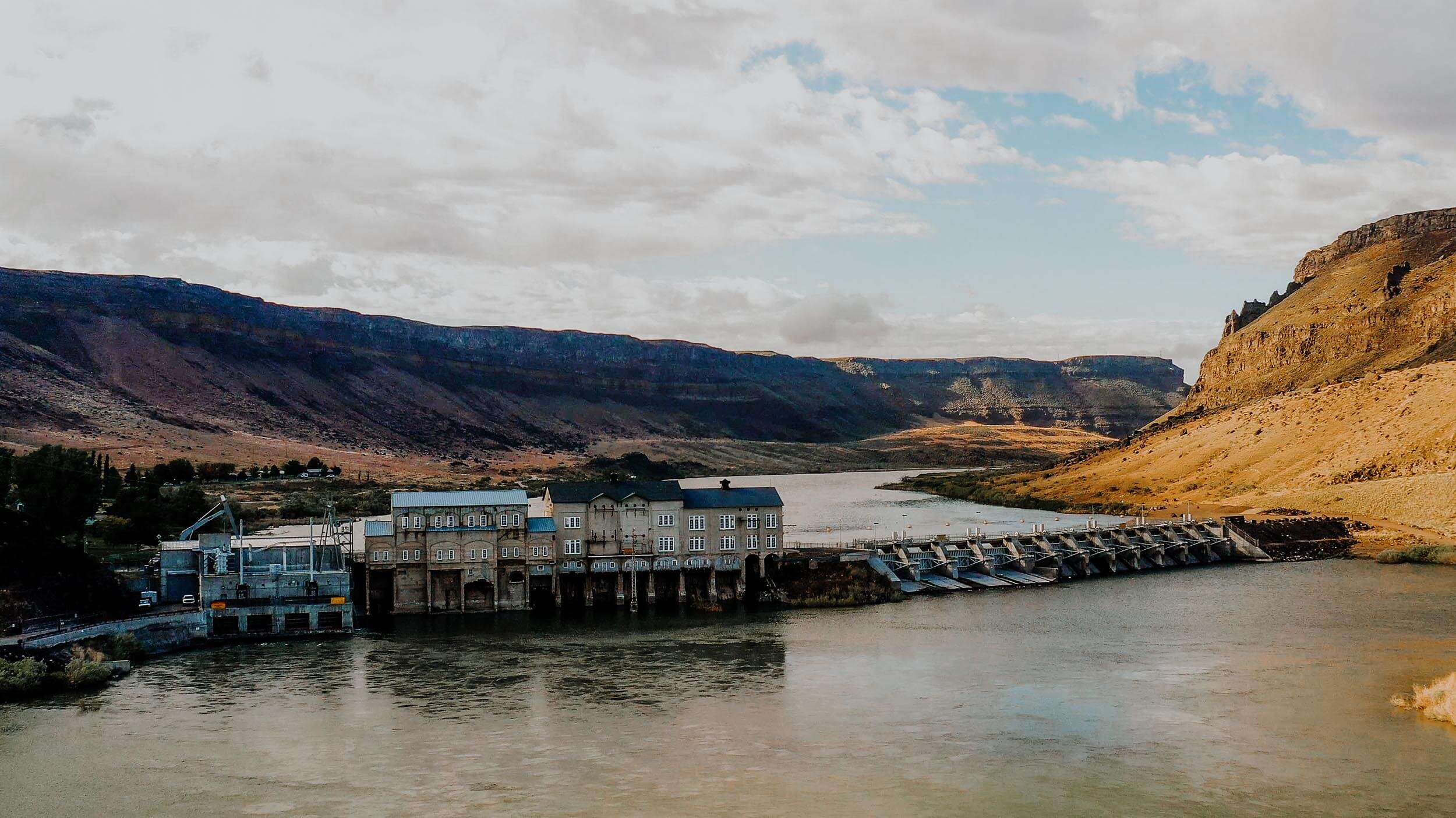 a dam stretching across a river, surrounded by a canyon